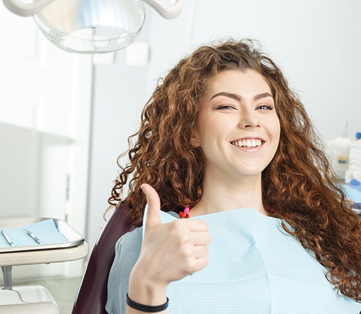 Female dental patient giving a thumbs up