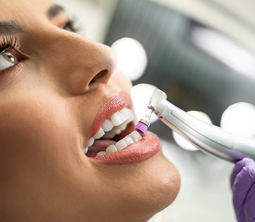 Woman receiving dental cleaning performed with electric dental brush