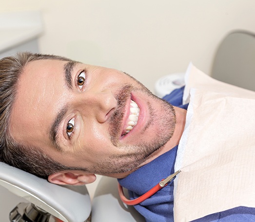 Man lying back in dental chair and smiling